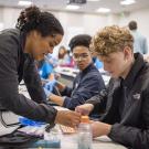 Elise Fannon, general surgery research resident at UC Davis Health, shows AvenueM students some tricks for suturing. 